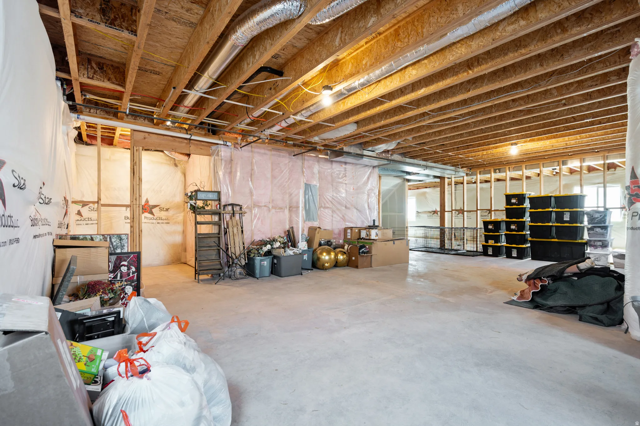 Expansive unfinished basement featuring exposed ceiling joists, concrete flooring, and partial wall framing