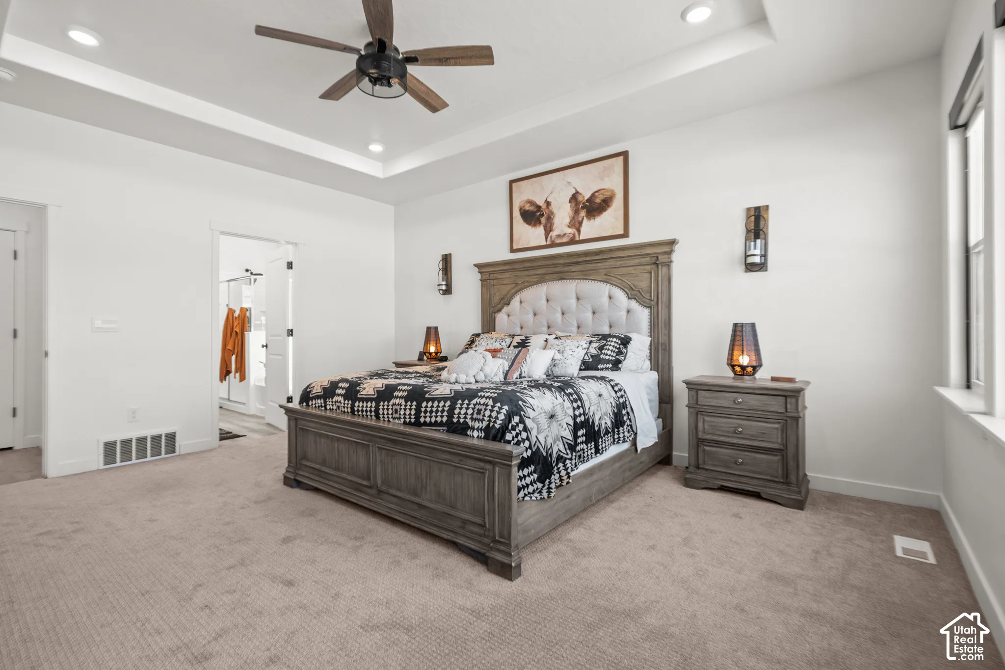 Spacious carpeted room featuring a ceiling fan, recessed lighting, and a tray ceiling