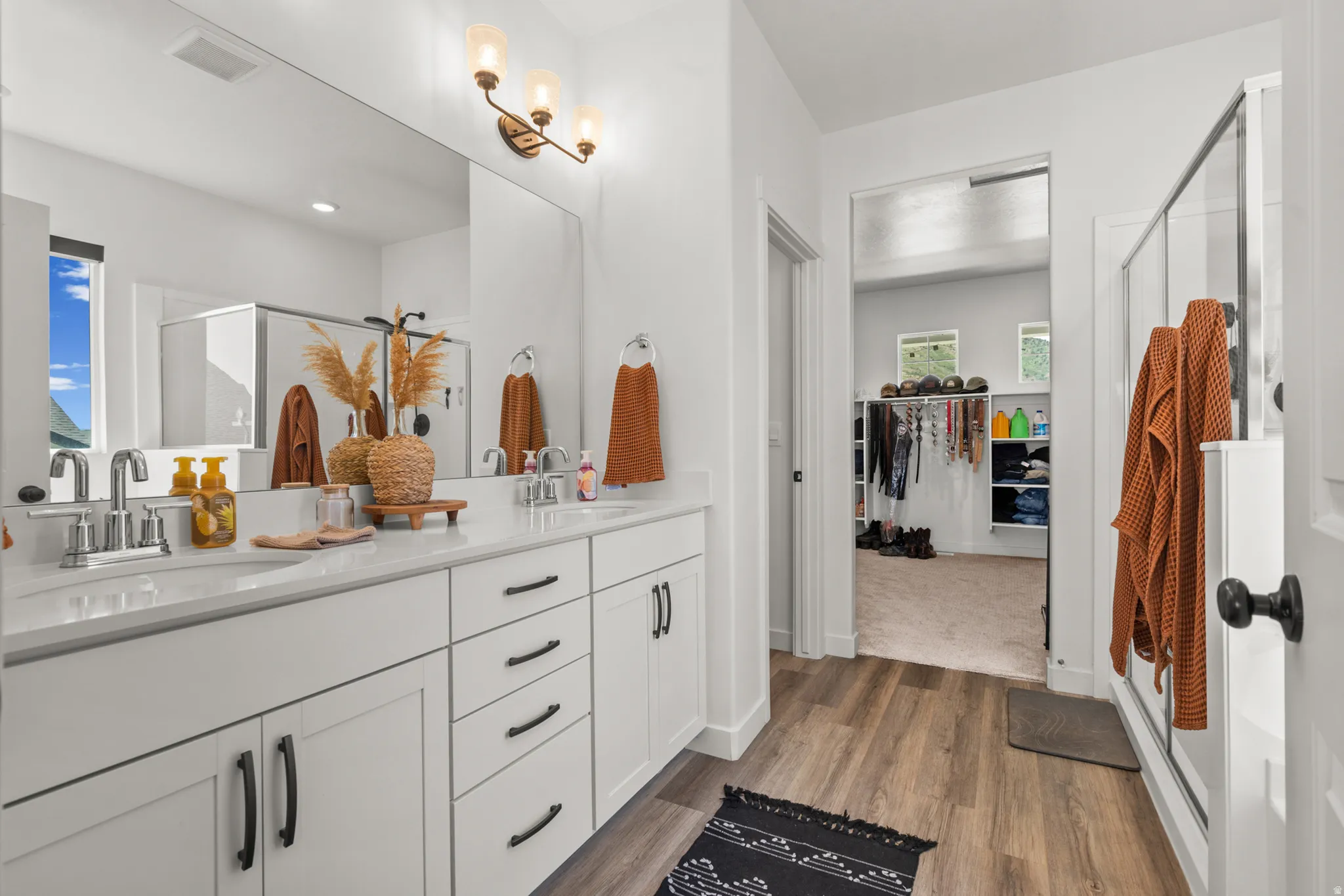 Bathroom featuring a dual vanity with white cabinetry, light-colored countertops, and chrome fixtures