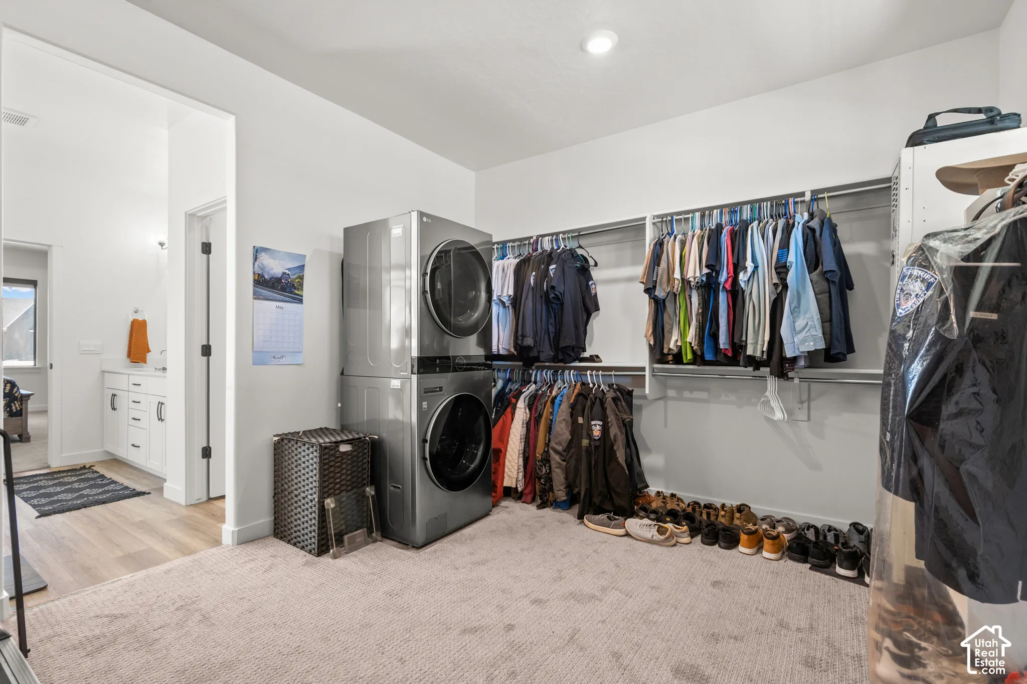 Spacious walk-in closet featuring stackable laundry units and extensive hanging storage