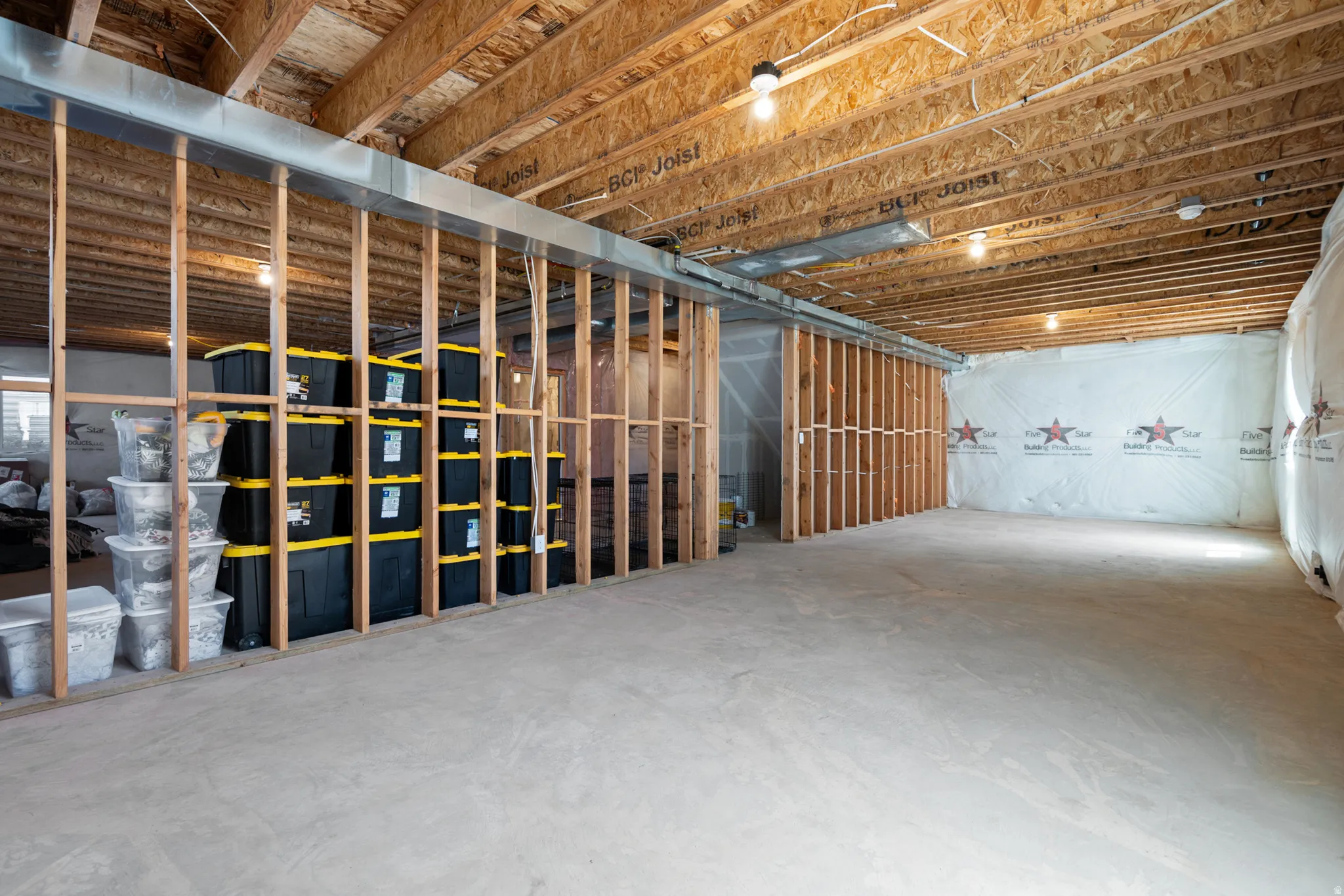 Unfinished basement featuring exposed wood joists, concrete flooring, and framed walls