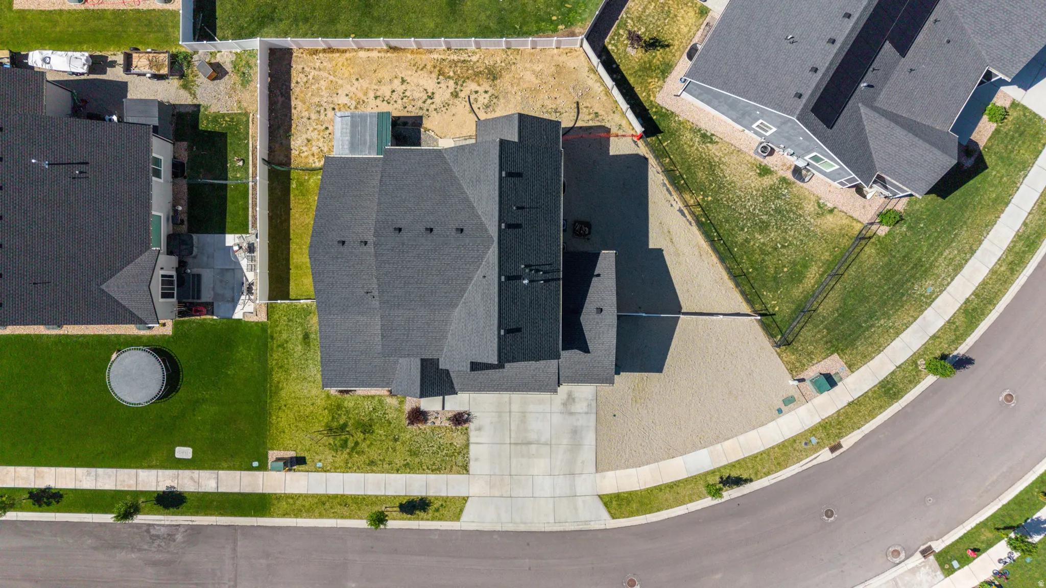 Aerial perspective showcasing a property with a dark shingle roof and a concrete driveway