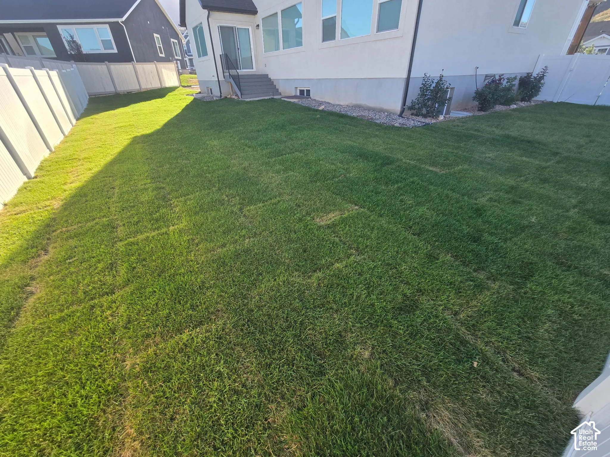 Expansive green lawn with a white privacy fence