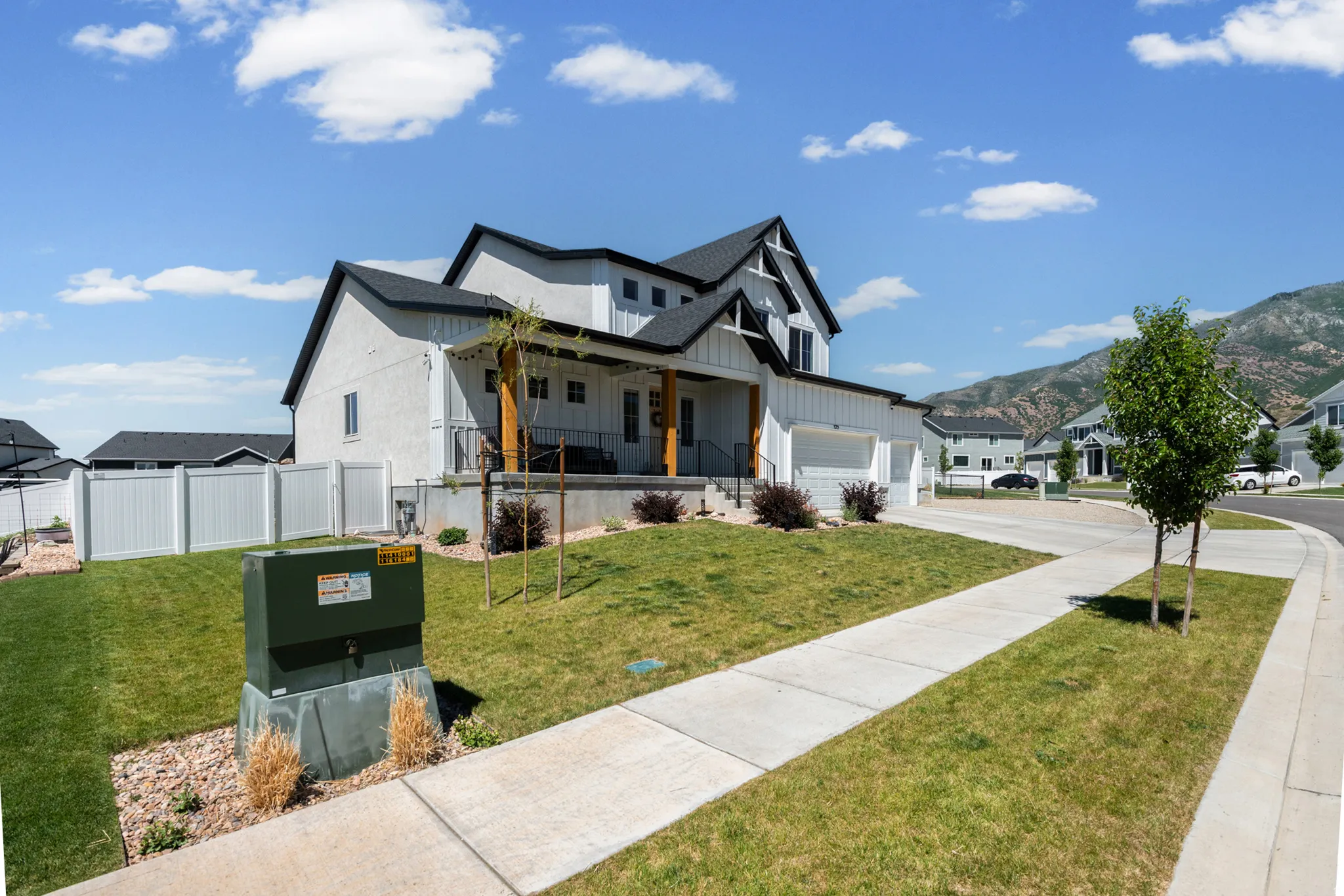 Modern farmhouse-style residence featuring a white board and batten facade, black-trimmed windows, a multi-gabled roofline, and an attached two-car garage