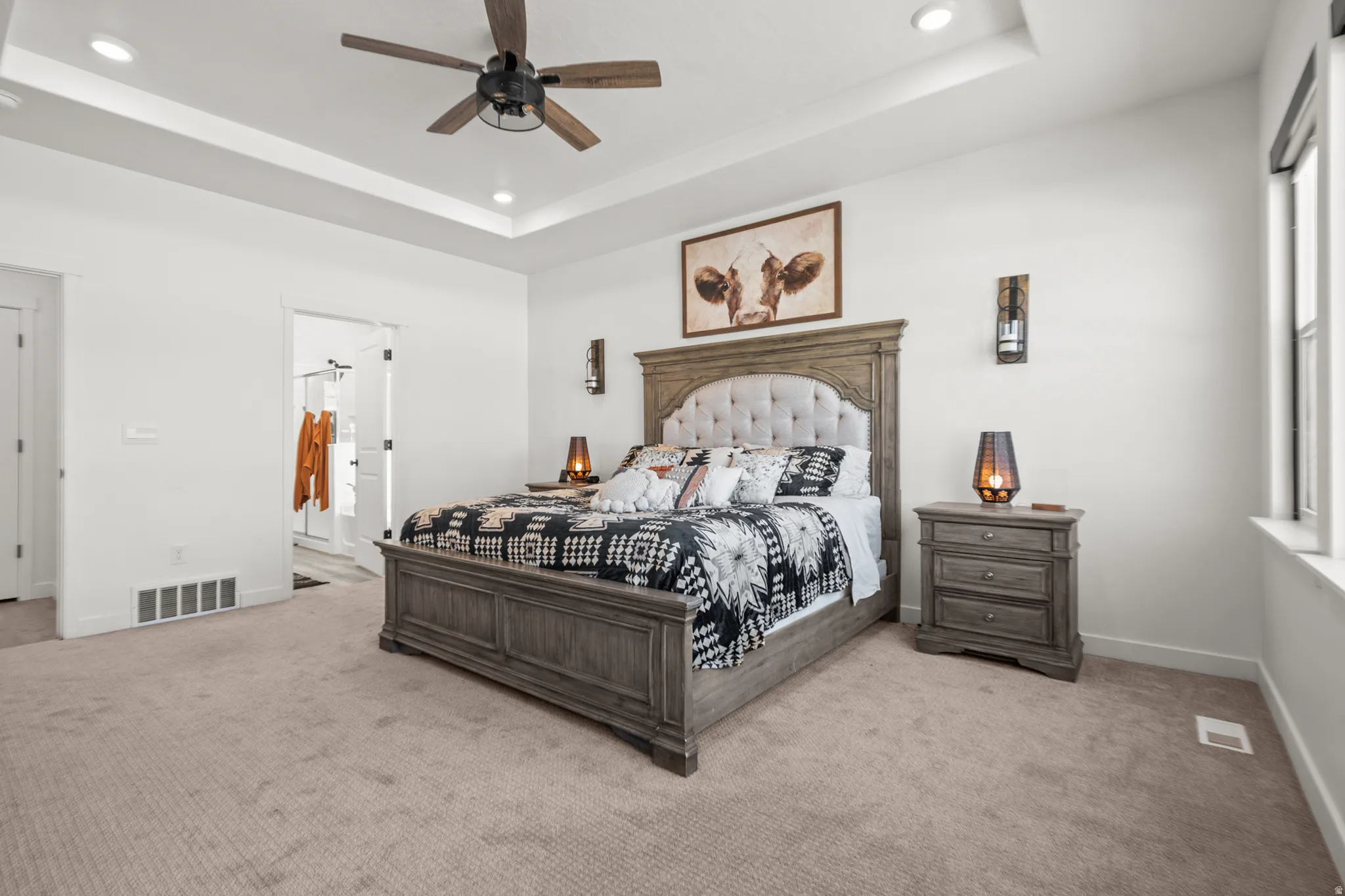 Spacious carpeted room featuring a ceiling fan, recessed lighting, and a tray ceiling