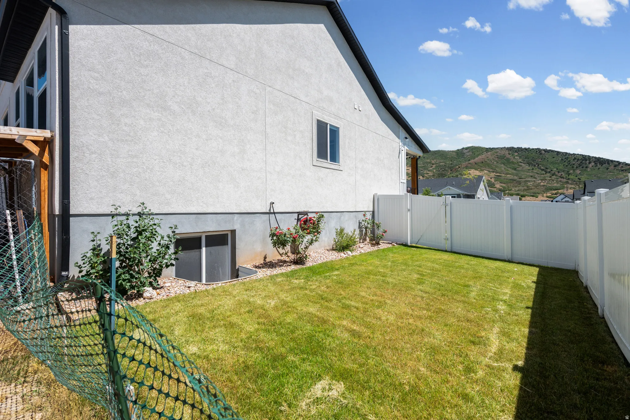 Fenced backyard with white vinyl fencing, and a window well