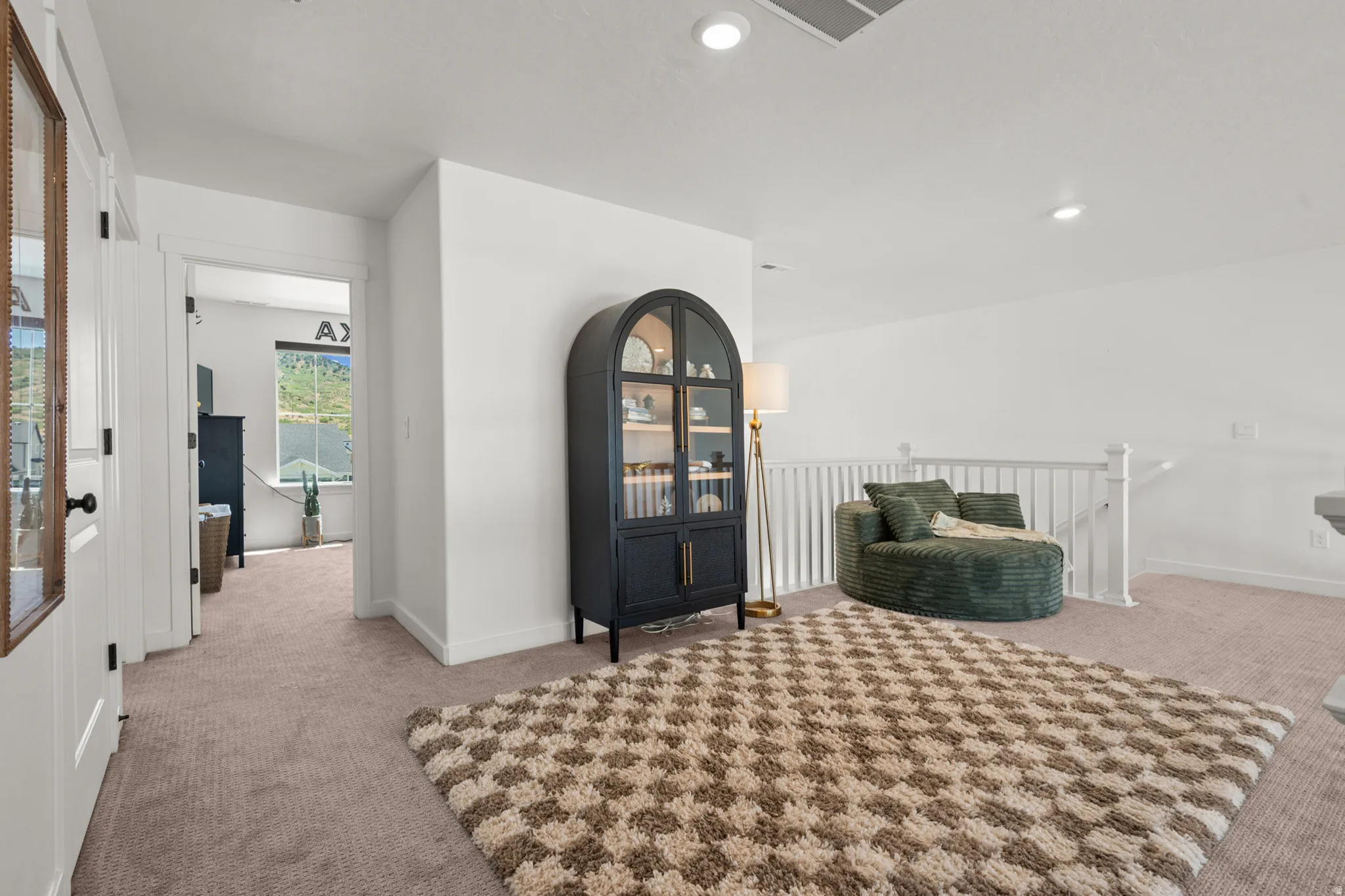 Open loft area featuring neutral-toned carpeting, white painted walls, and a white railing system