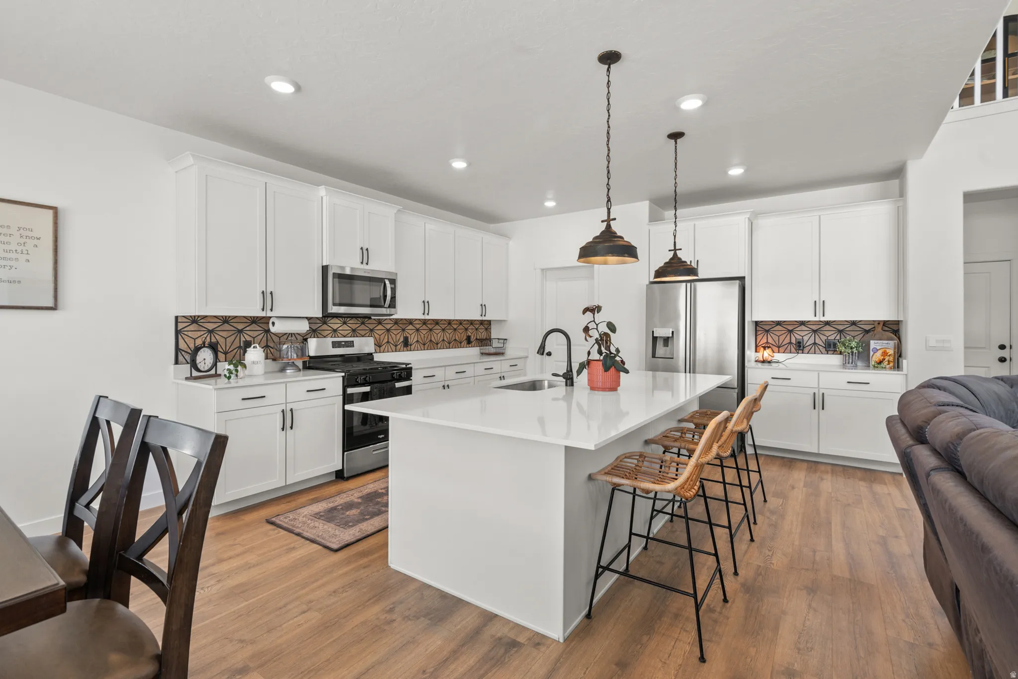 Contemporary kitchen featuring an expansive island with a white countertop and seating for three