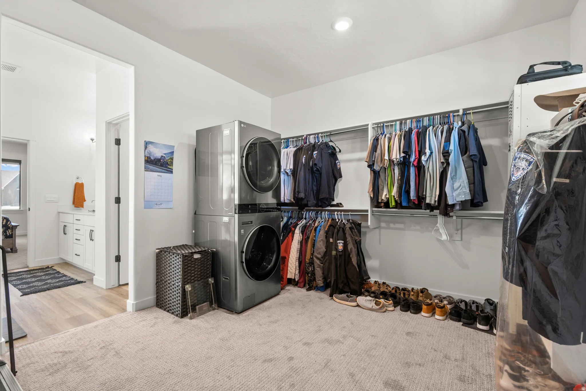 Spacious walk-in closet featuring stackable laundry units and extensive hanging storage
