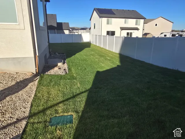 Expansive grassy yard with full vinyl fencing and gravel landscaping along the property perimeter