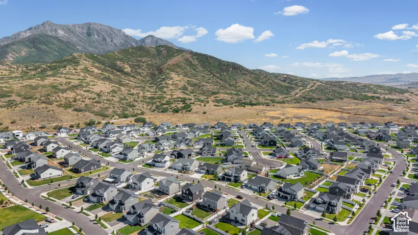 Expansive residential development featuring numerous single-family homes with gray and white exteriors, dark shingle roofs, and green lawns
