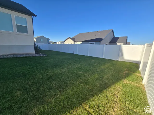 Expansive lawn area with a white privacy fence