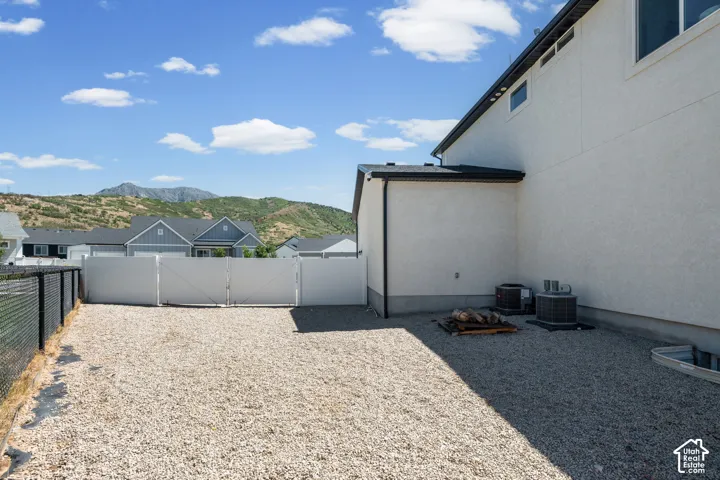 Expansive gravel side yard with partial chain link fencing and a white privacy fence