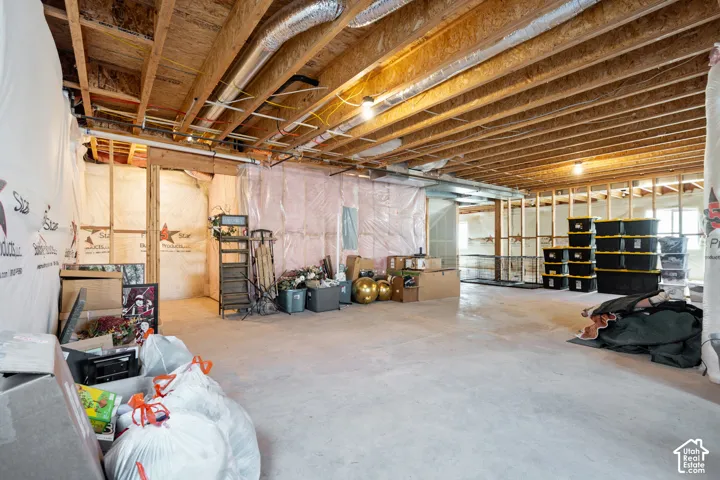 Expansive unfinished basement featuring exposed ceiling joists, concrete flooring, and partial wall framing