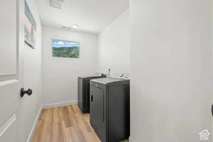 Dedicated utility space featuring wood-finish flooring, a rectangular window, recessed lighting, and a white interior door with matte black hardware