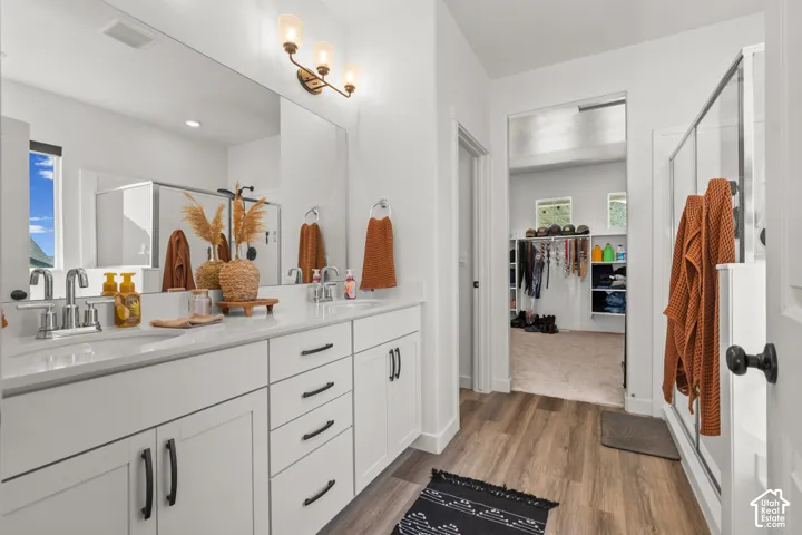 Bathroom featuring a dual vanity with white cabinetry, light-colored countertops, and chrome fixtures