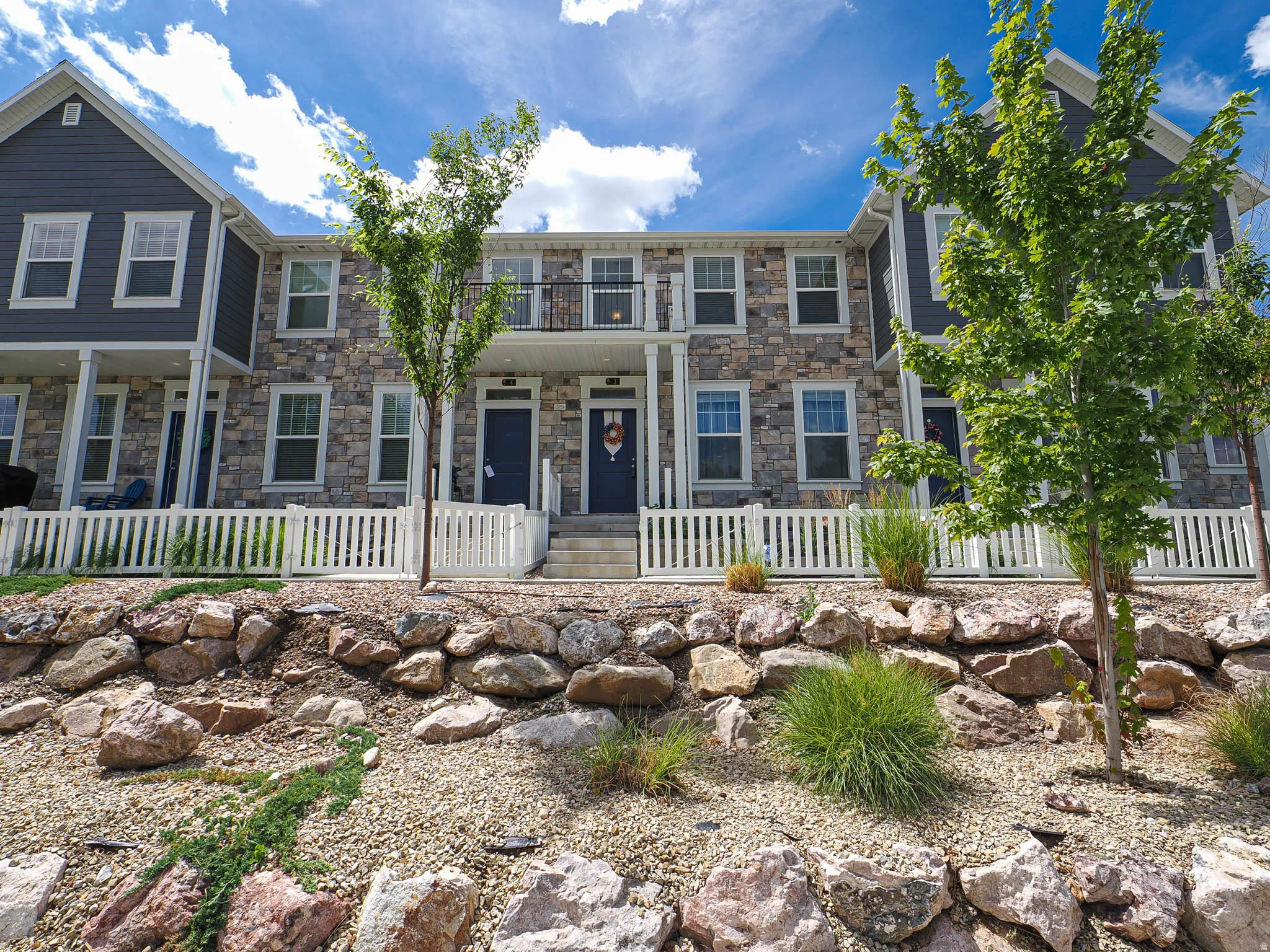 Stone and siding exterior with white window trim and a black balcony railing