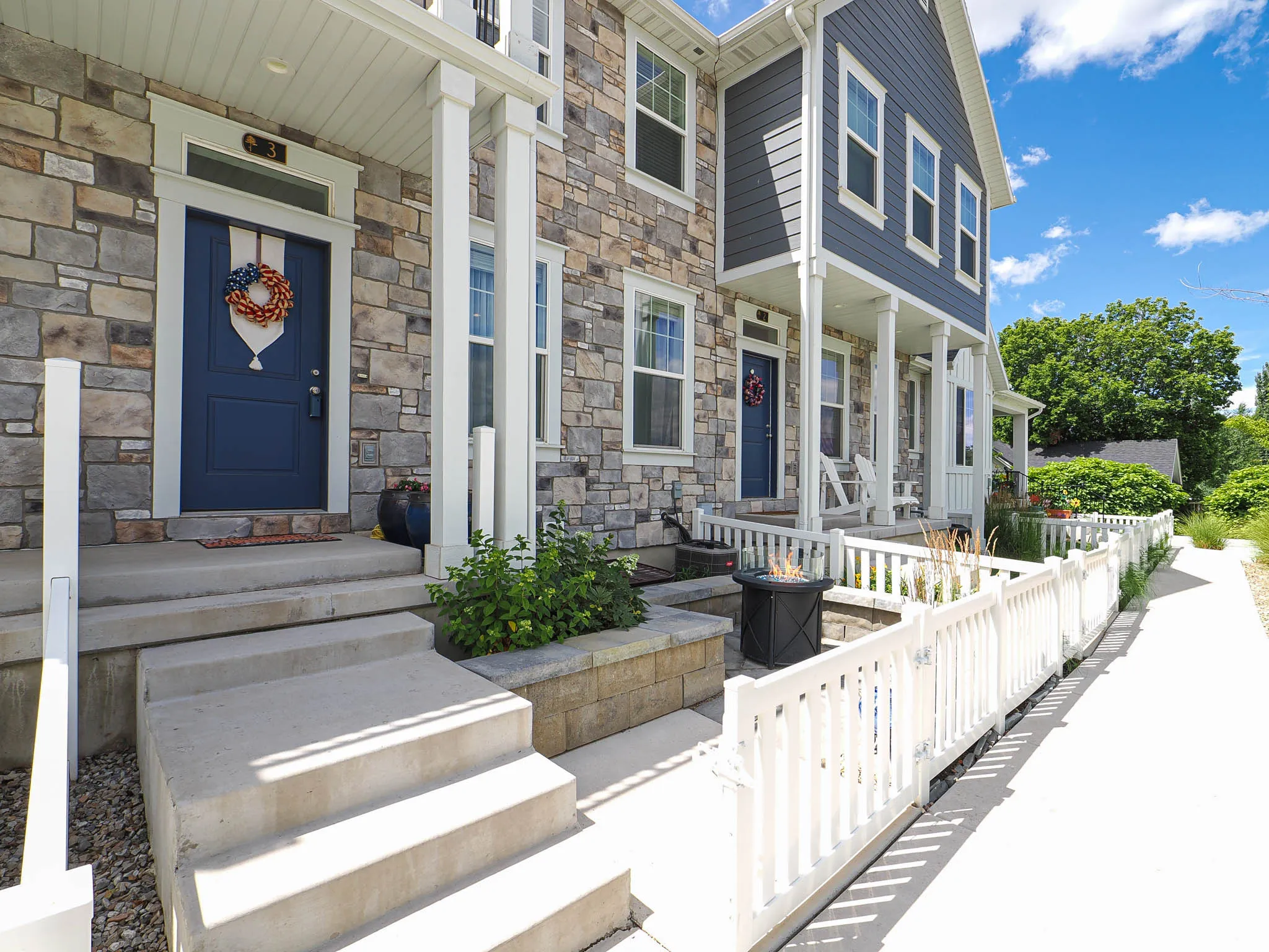 Stone and siding exterior with a navy blue entry door, white trim, and concrete steps
