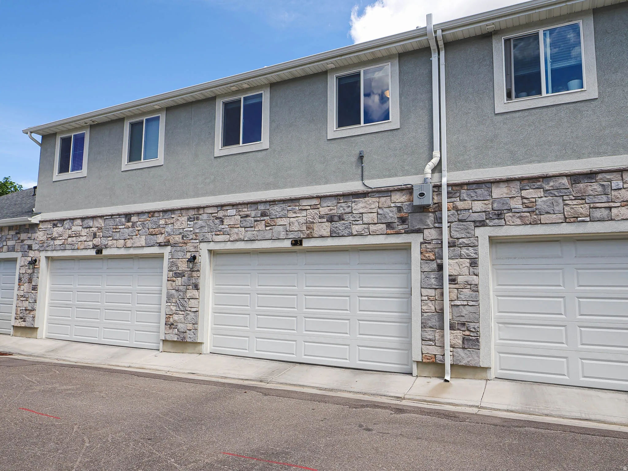 Multi-unit exterior showcasing a stone facade and stucco upper level