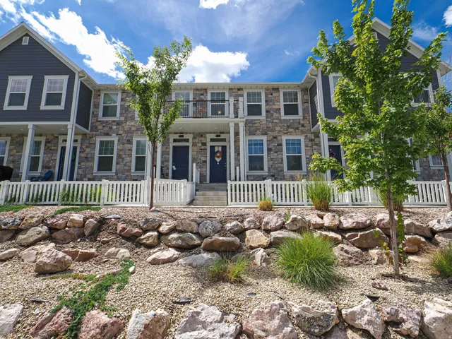 Stone and siding exterior with white window trim and a black balcony railing