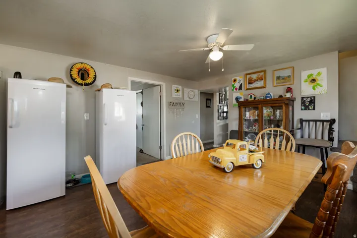 Dining area featuring wood-finish flooring, a ceiling fan with integrated lighting, and a doorway leading to an additional interior space