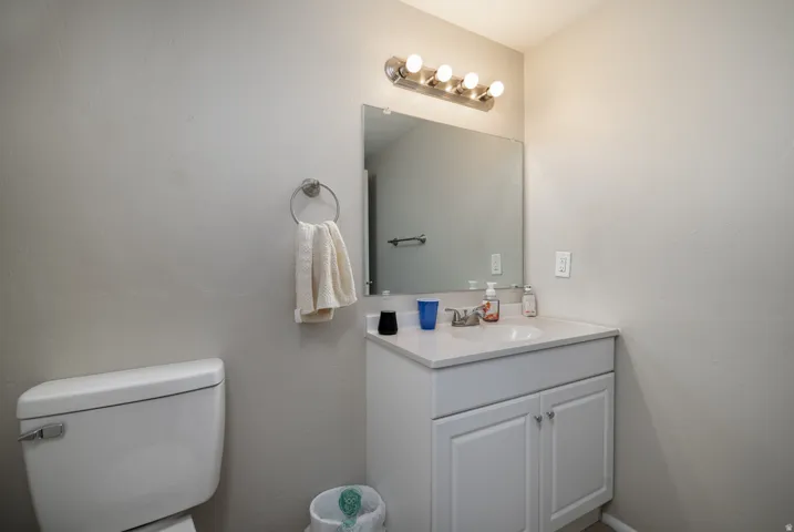 Bathroom vanity featuring a single basin sink, white cabinetry, a large wall-mounted mirror, and vanity lighting