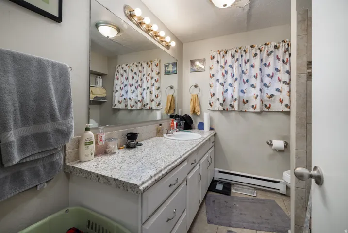Vanity featuring a speckled countertop, integrated sink, and white cabinetry