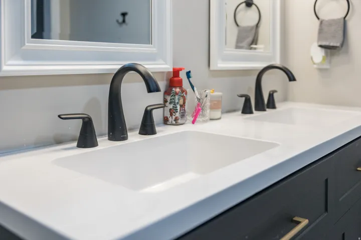 Double vanity featuring integrated white sinks, matte black faucets, and a light-toned countertop