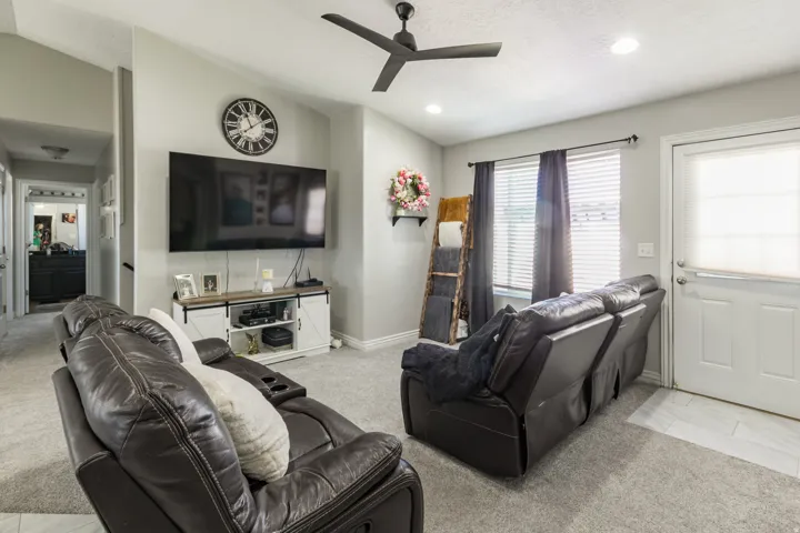 Carpeted living area featuring vaulted ceilings with a ceiling fan and recessed lighting