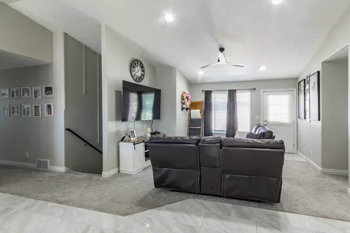 Vaulted ceiling living area featuring recessed lighting, a ceiling fan, light gray painted walls, and gray carpeting