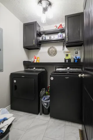 Dedicated laundry area featuring a built-in countertop, two upper cabinets, and open shelving