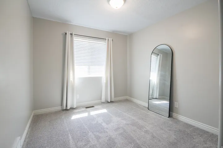 Neutral-toned room featuring a single window with blinds and curtains