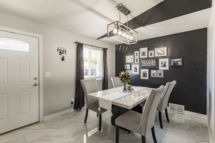 Dining area featuring a dark accent wall, white-paneled door with an arched glass insert, light-toned tile flooring, and a rectangular ceiling light fixture