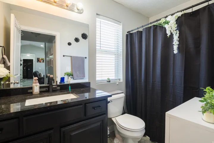 Bathroom vanity featuring a black granite countertop with an undermount sink, matte black faucet, and dark cabinetry