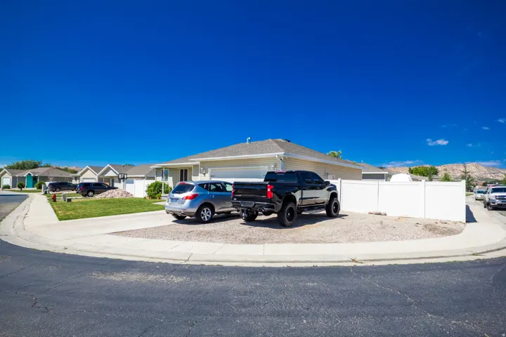 Corner lot with an attached garage, featuring a gravel side yard and a white privacy fence