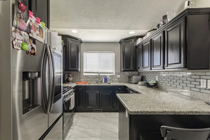 Kitchen featuring dark wood cabinetry, light-toned granite countertops, and a subway tile backsplash