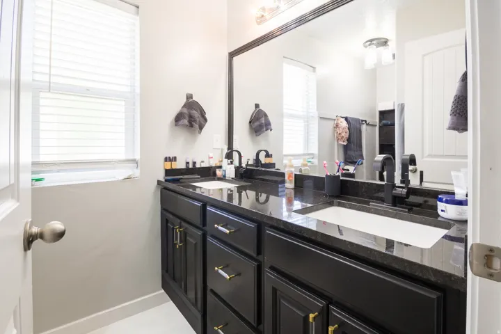 Dual vanity with dark cabinetry, integrated sinks, black faucets, and dark countertop