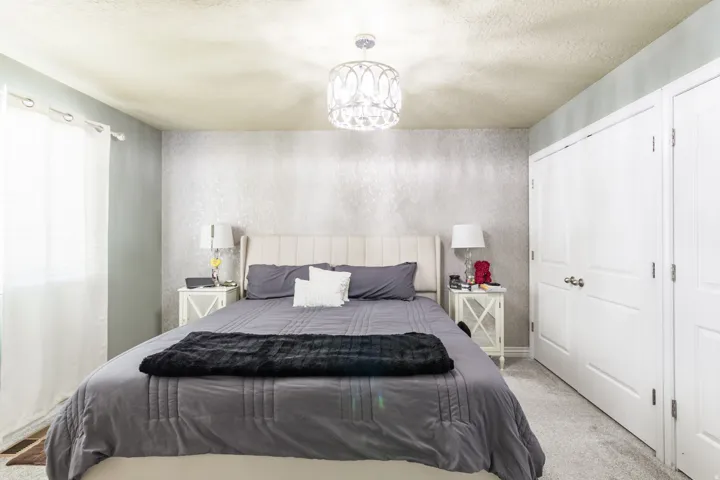 Bedroom featuring a textured accent wall, chandelier lighting, and a neutral color palette