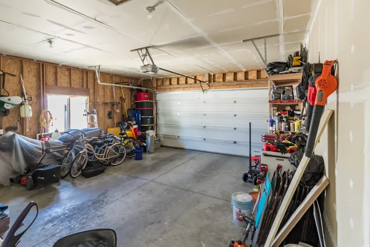 Spacious garage featuring a concrete floor, overhead lighting, an automatic garage door opener, and a rear window for natural light