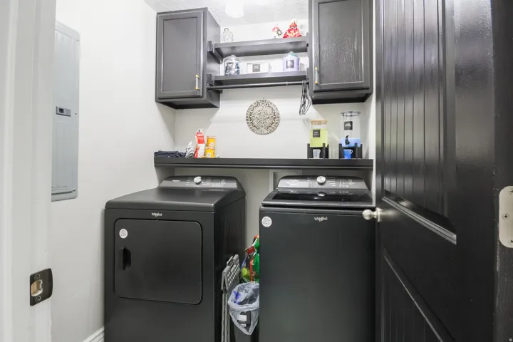 Dedicated laundry area featuring dark cabinetry, an integrated shelf, and an overhead hanging rod