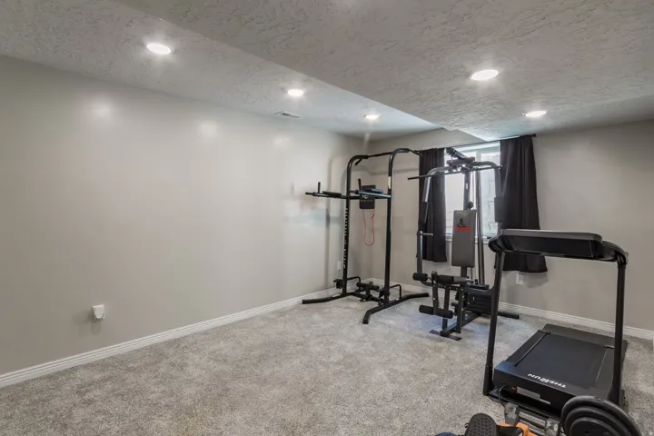 Carpeted room with recessed lighting and a window featuring black blinds