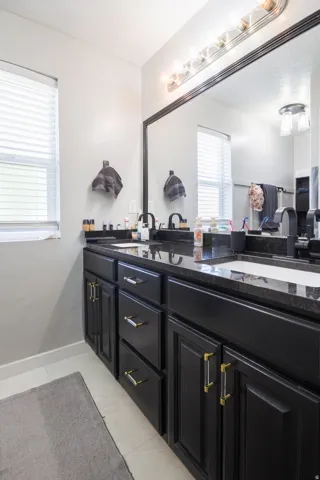 Dual sink vanity with black cabinetry and golden-toned hardware