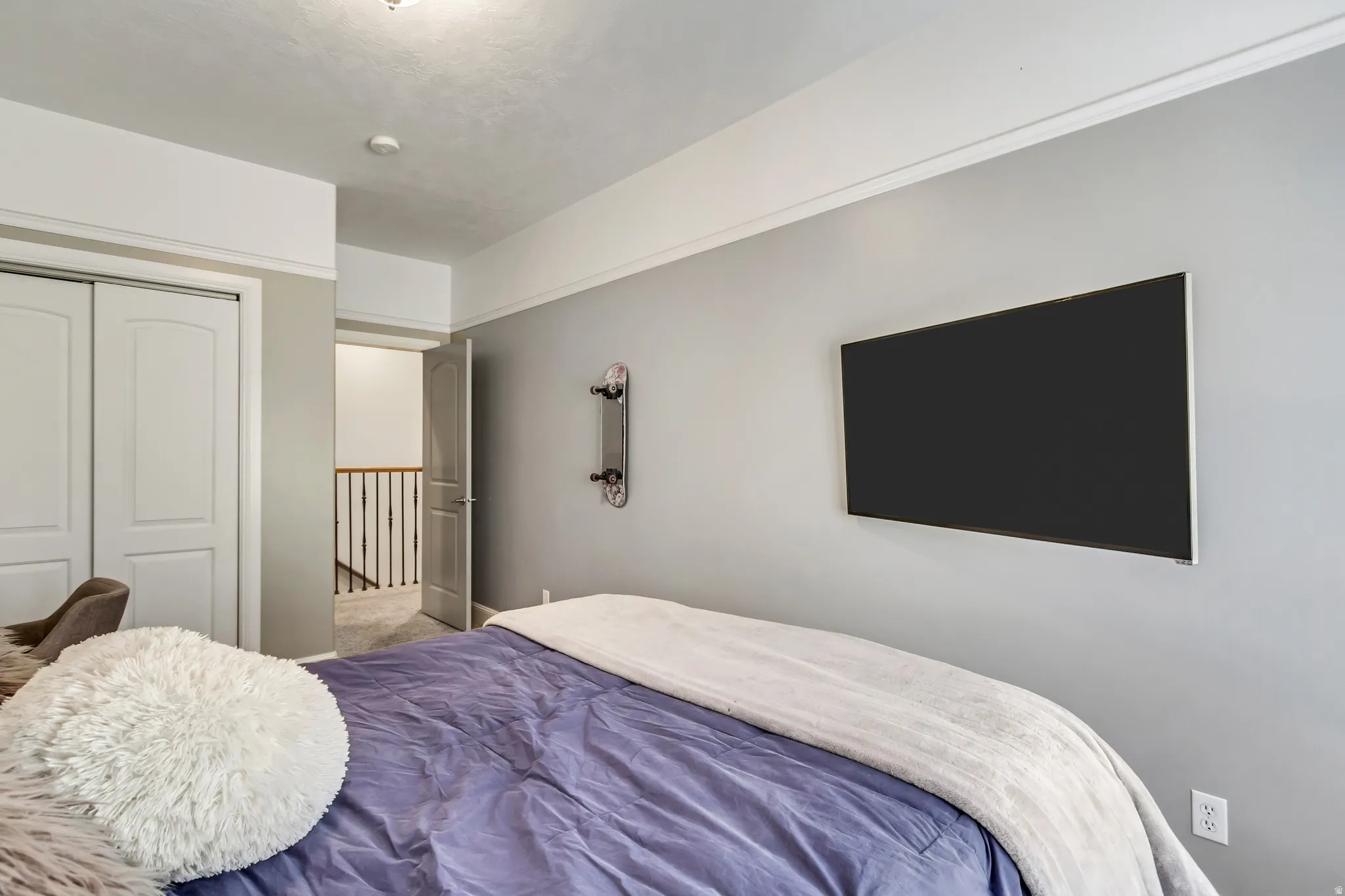 Bedroom featuring light gray walls, white crown molding, and a mounted flat-panel display