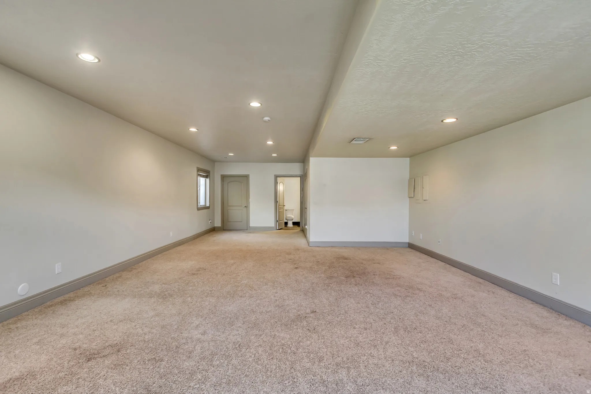 Spacious room featuring neutral carpeting and light-colored walls