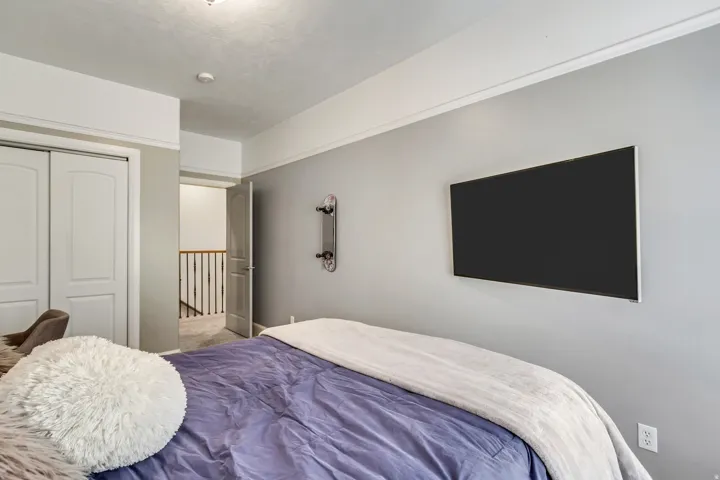 Bedroom featuring light gray walls, white crown molding, and a mounted flat-panel display