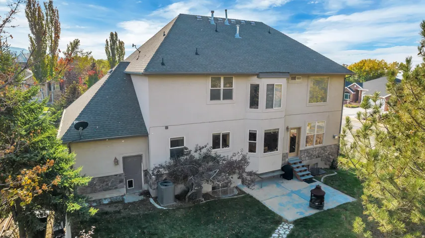 Rear exterior featuring a multi-level design with a stucco and stone veneer finish
