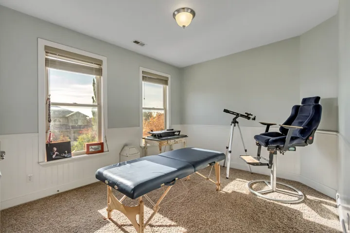 Room with wainscoting and light-colored carpeting, featuring two windows with natural light