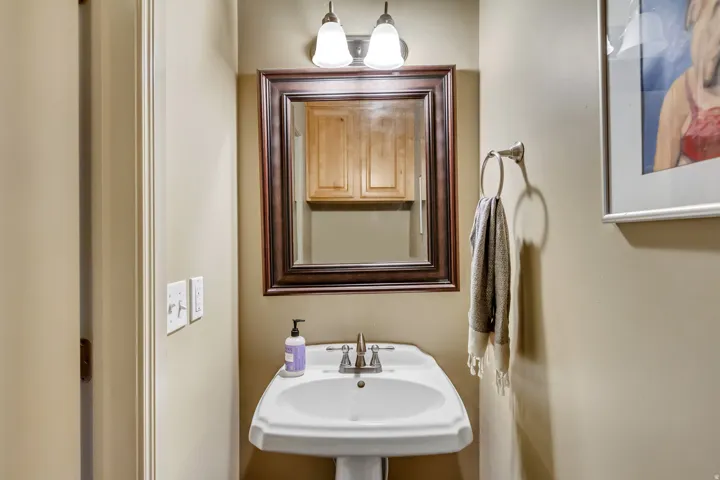 Pedestal sink with polished chrome faucet and a framed mirror