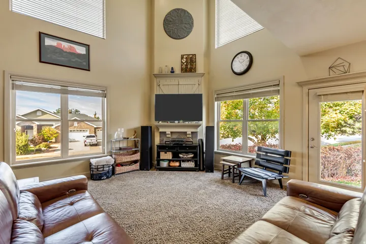 Living area featuring vaulted ceilings, abundant natural light from multiple windows, a corner media center with built-in cabinetry, and neutral-toned carpeting