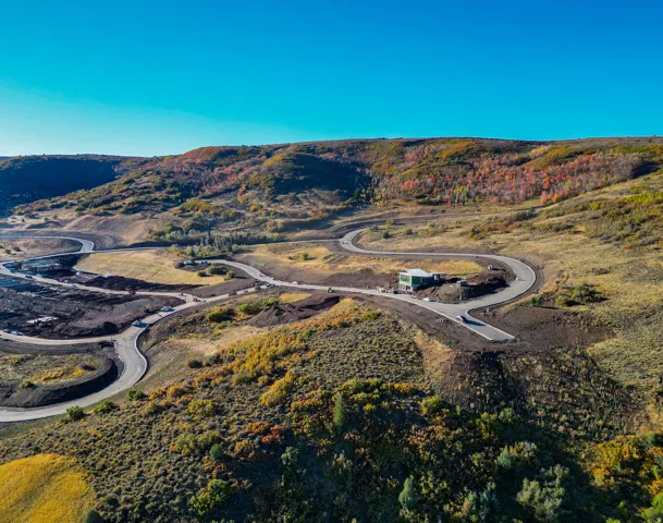 Expansive mountain landscape featuring winding roads and a contemporary structure